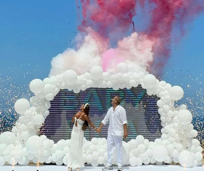 An outdoor celebration with white balloons and pink confetti