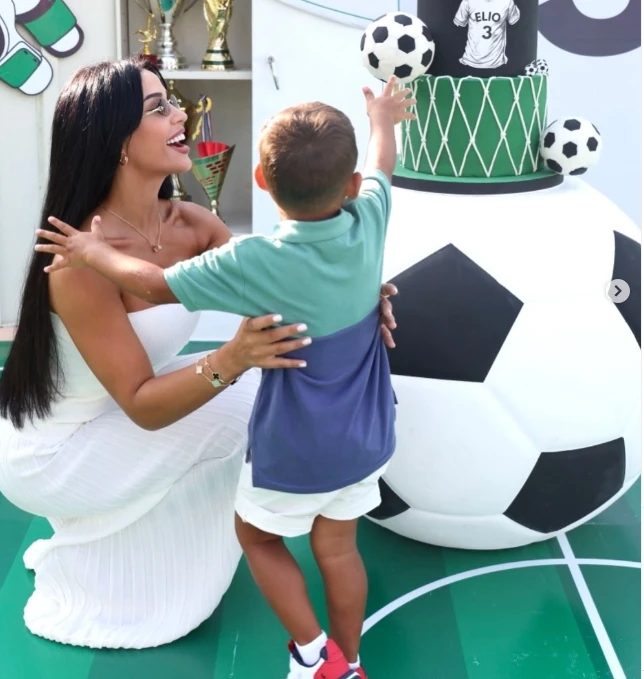A mother and child beside a football birthday cake